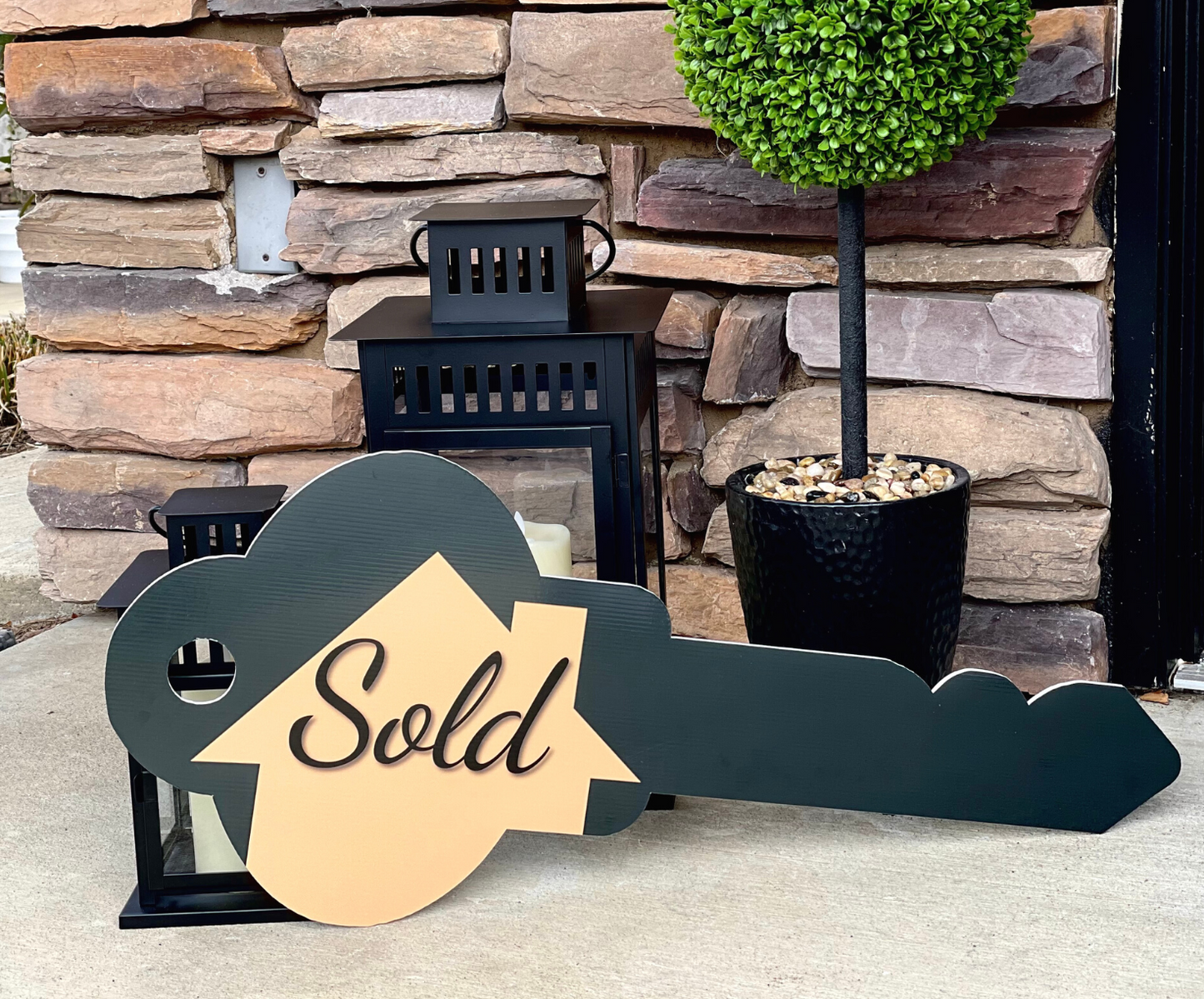 Key-shaped double-sided Sold prop sign displayed against a stone wall with lanterns
