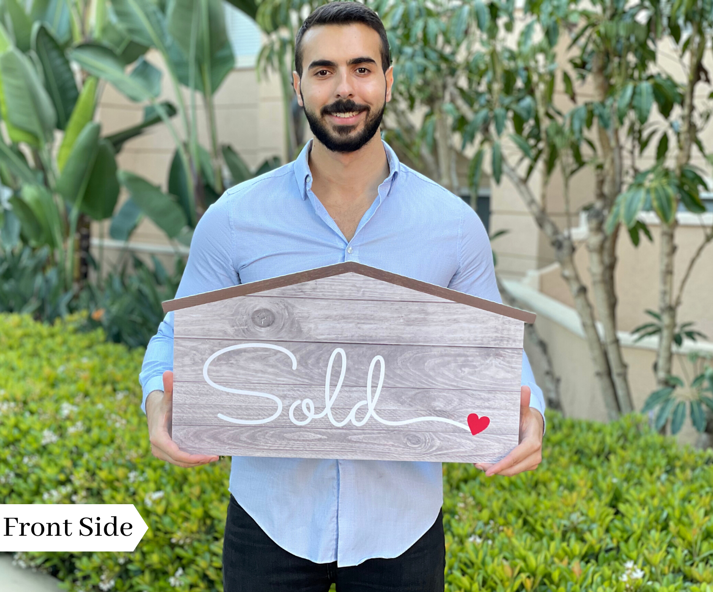 Realtor holding the front side of a 24 inch house-shaped Sold prop sign outdoors