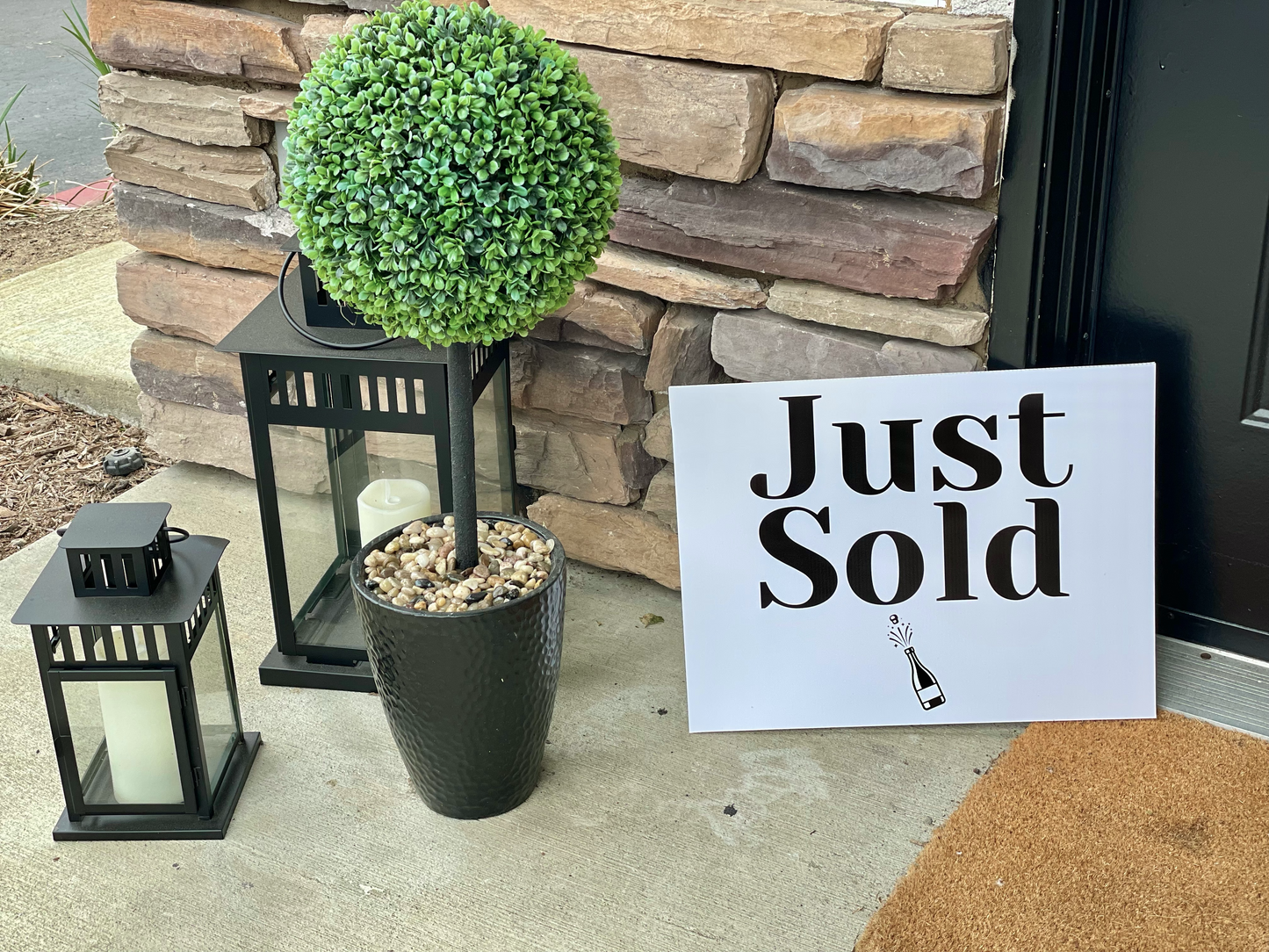 Rectangle Just Sold prop sign displayed on a stone porch with lanterns and a potted plant