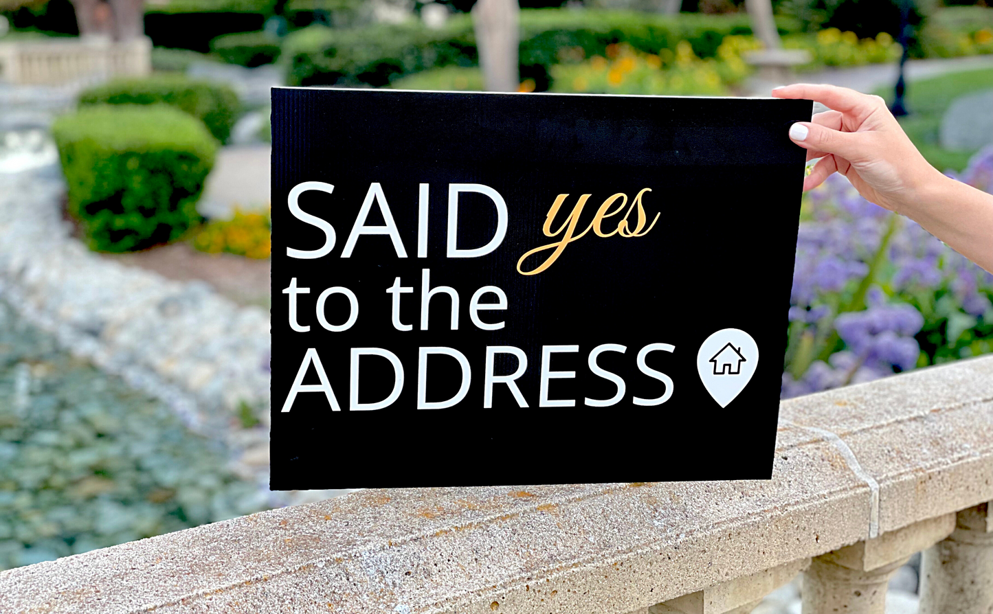 Realtor placing a Said Yes to the Address rectangle prop sign on a stone ledge outdoors